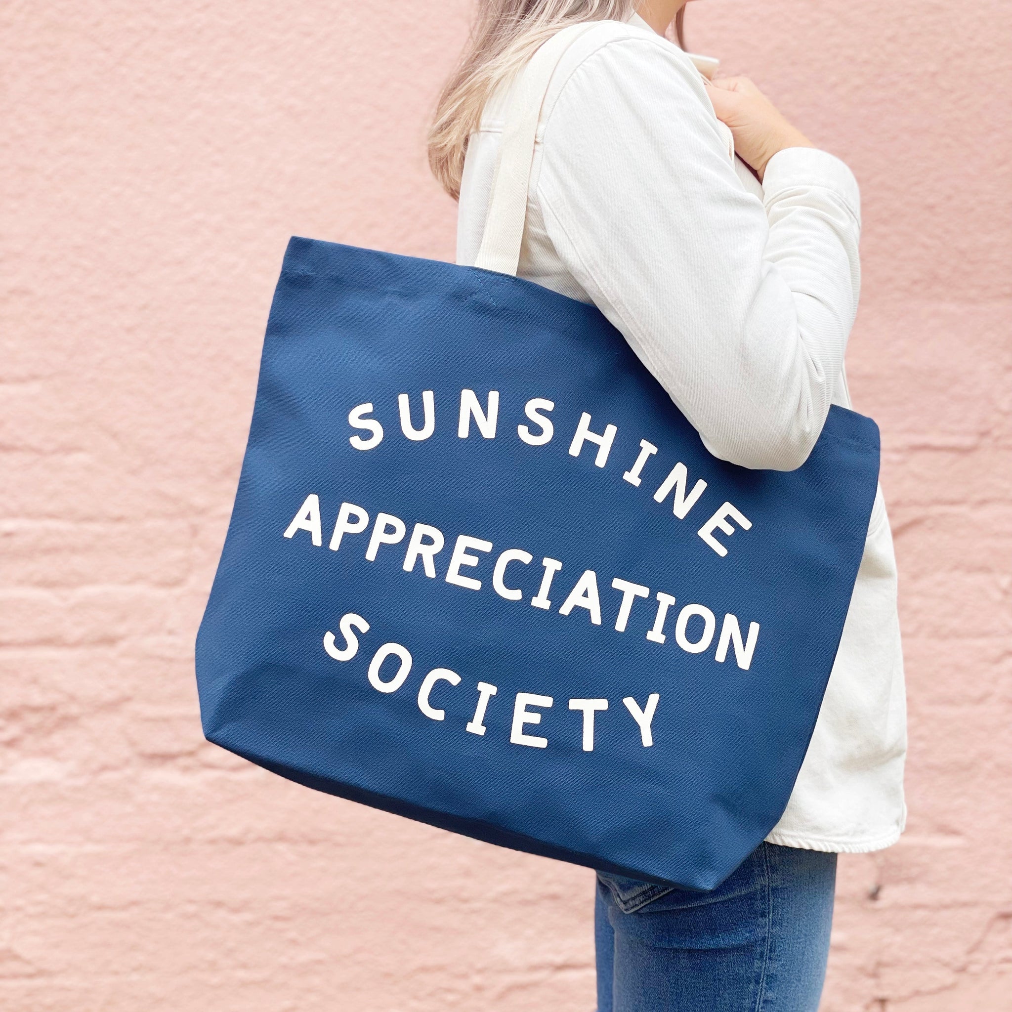 Large blue tote bag with sunshine appreciation sociaty slogan and white handle 