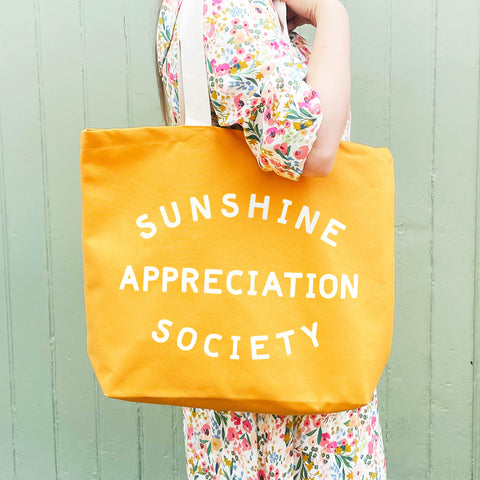 Yellow canvas tote bag with sunshine appreciation society slogan and white handle