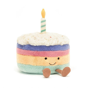 Soft fleece faux fur birthday cake doll with smiley face and little legs in corduroy. Ranbow layered cake with one candle. Cuddly plush toy.  