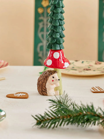 Ceramic candle holder in the shape of hedgehog holding red and white mushroom 