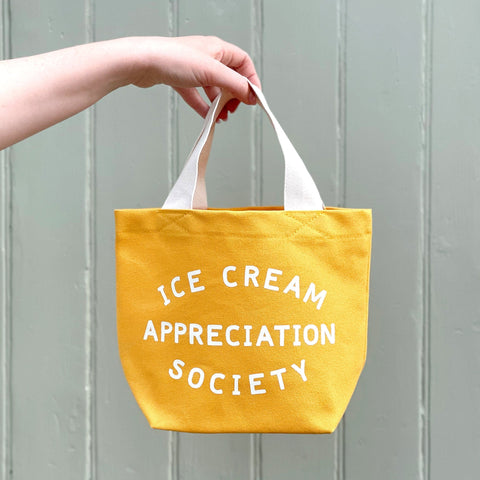 Small yellow cotton canvas tote bag with ice cream appreciation society slogan and white handle