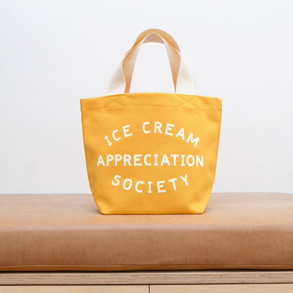Small yellow cotton canvas tote bag with ice cream appreciation society slogan and white handle