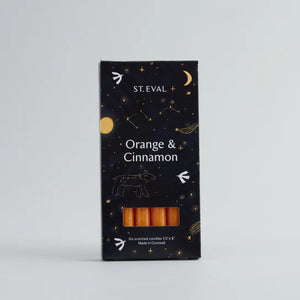 A set of six orange & cinnamon scented candles in a navy blue box with constellation illustration