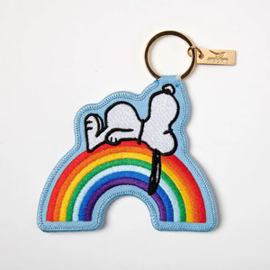 Embroidered applique key charm in light blue with Peanuts Snoopy lying on a rainbow