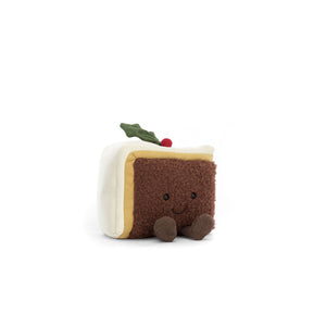 A slice of christmas cake in brown with white icing, holly leaf and berry on top, smiley face and littel legs 